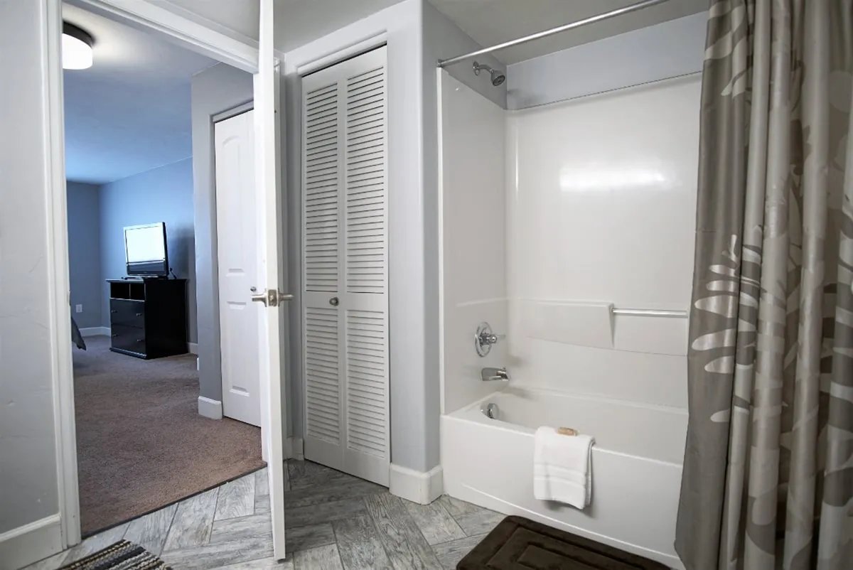 A bright, inviting bathroom with a bathtub and shower combo, plush towels, and a nearby closet door. The space feels clean and refreshing, suitable for both a relaxing soak or a quick shower after an active day.