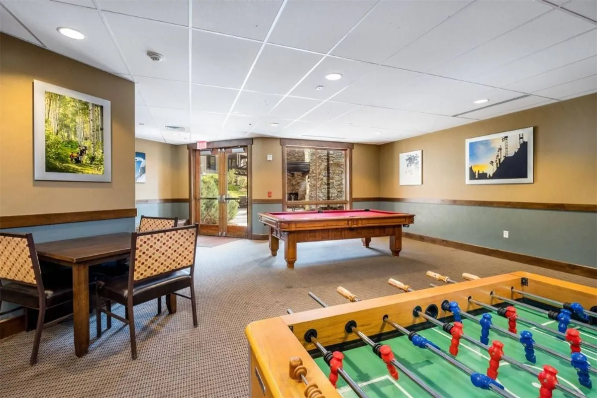 A vibrant game room featuring a pool table, foosball table, dining area, and colorful artwork. The space feels lively and welcoming, inviting guests to engage in friendly competition or socialize over a meal.
